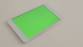 Silver tablet computer on white reflective background displaying chroma green screen 4K 2160p UltraHD footage - Tablet PC greenscreen display on white surface modern 4K 3840X2160 UHD video
