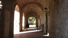 Video of stone arched walkway of old Spanish Mission Concepcion in San Antonio, Texas. Visitor walk past open arch. Built in early 1700â€™s by missionaries from Spain and local Indians.  