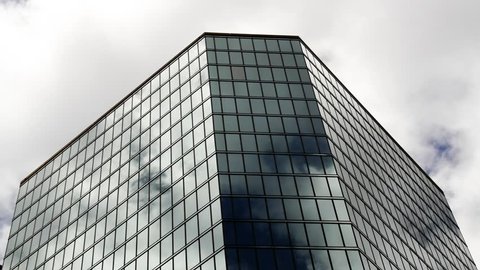 Office building with reflective glass and fast moving clouds
