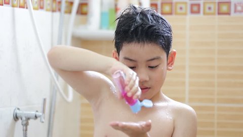Little asian boy uses moisturizer in bathroom after having a shower