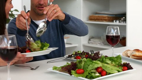 Man serving salad to his wife during lunch in the kitchen