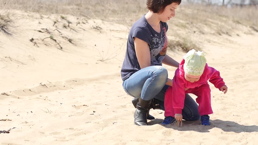 Mother with a child in steppe desert nature playing with sand
