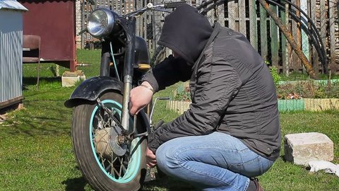 Man with wrench near old motorcycle