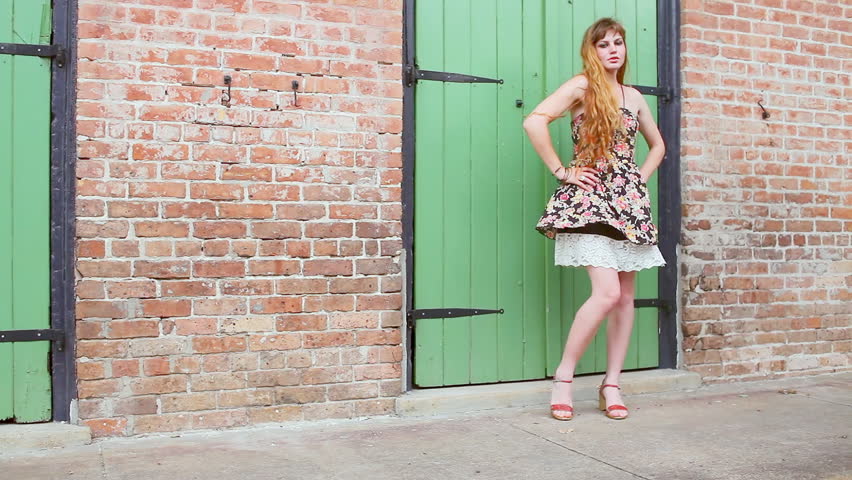 Young woman stands seductively on a sidewalk