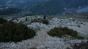 Bay of Kotor with bird eye view. Aerial video of Tivat, Muo, Perast, Prcanj, and all the Bay of Kotor in Montenegro. Sunset in the Montenegrin mountains. View from Mount Lovcen. The girl on the bench