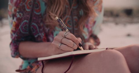 Cropped shot of a boho girl wearing a floral dress writing in her diary