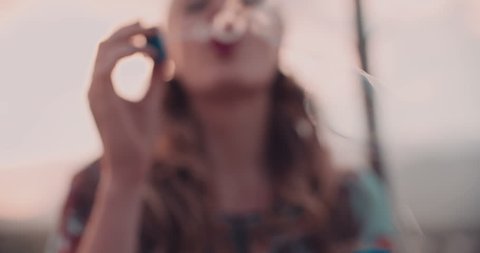 Boho girl blowing bubbles, focused on foreground bubbles
