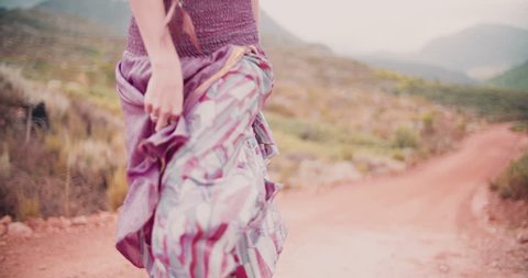 Cropped shot of a boho girl walking in a purple skirt with a feathered dream catcher as jewellery