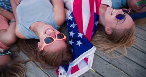 Teens friends on summer vacation lying down with an American flag , Panning in Slow Motion Video stock