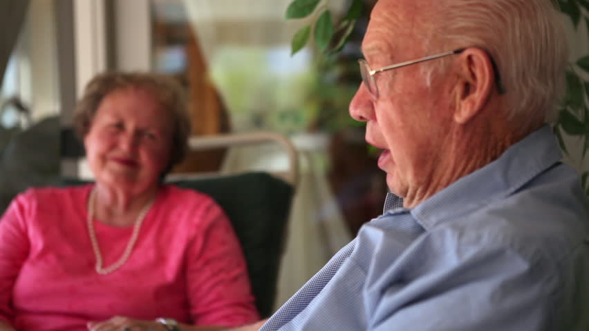 A shot of an elderly man and woman laughing as they tell a story.