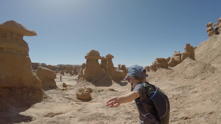 Families walking through goblin valley state park in the hot desert of southern Utah.  Shot using a gimbal for stabilization