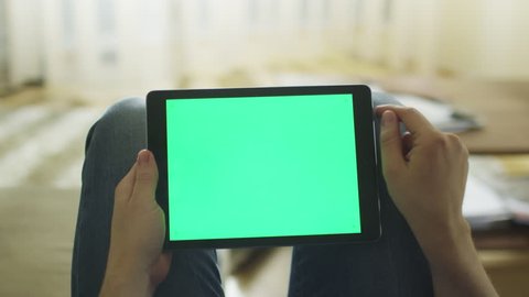 Man is Laying on Couch at Home and Using Tablet with Green Screen in Landscape Mode on Lap. Shot on RED Cinema Camera in 4K (UHD).