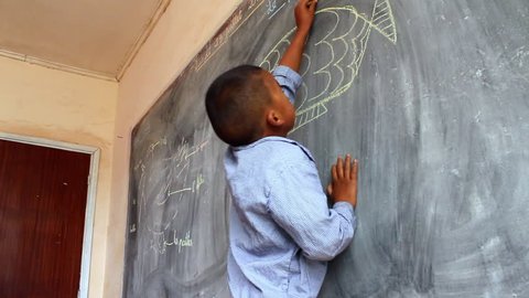 Mahajanga, Madagasgar - CIRCA 2013 - Shot of young boy drawing a fish on a chalkboard in classroom.