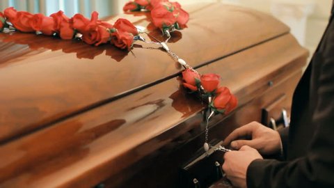 Coffin at funeral service or wake, person giving last respects to deceased 