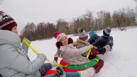 Six people ride on top of inner tubes by snow at winter day. Aerial view