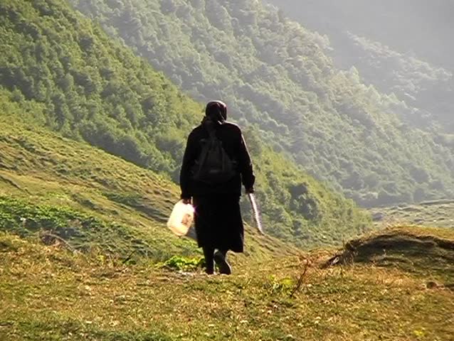 Old Georgian woman going with her dog. 