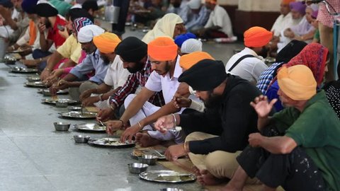 AMRITSAR, INDIA - SEPTEMBER 27, 2014: Unidentified poor indian people eating free food at a soup kitchen in the Sikh Golden Temple