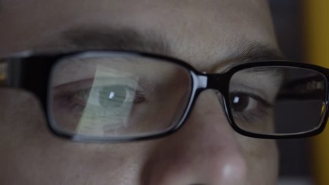 Close up of man's eye's and glasses. A reflection of him typing on a smart phone is seen. Filmed in 4K UHD.