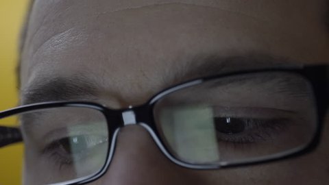 Close up of man's eye's and glasses. A reflection of him typing on a smart phone is seen. Filmed in 4K UHD.