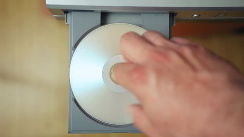 loading and unloading laser disc from the DVD/CD player. Man of hand  loads laser disc into the device and remove the disk from the laser device