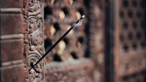 A burning incense stick placed on the intricate wooden carvings of the Pashupatinath (Yaksheswor Mahadev) Temple in Bhaktapur, Nepal. Bhaktapur is listed as World Heritage Site by UNESCO.