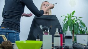 Woman enjoying in the beauty salon . Slow motion total RAW footage of a woman seating in the beauty salon and getting her make up done.
