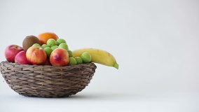 Footage of colorful fruits in a wicker basket isolated on white background