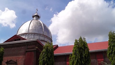 SAN PABLO CITY, LAGUNA, PHILIPPINES - APRIL 26, 2015: Dome of old spanish time cathedral still stands below moving clouds and blue sky time lapse