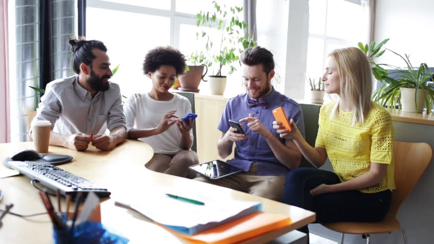 business, technology, people and communication concept - creative team with smartphones and tablet pc computer in office