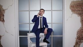 Businessman sitting on a symbolic career ladder and talking on the phone