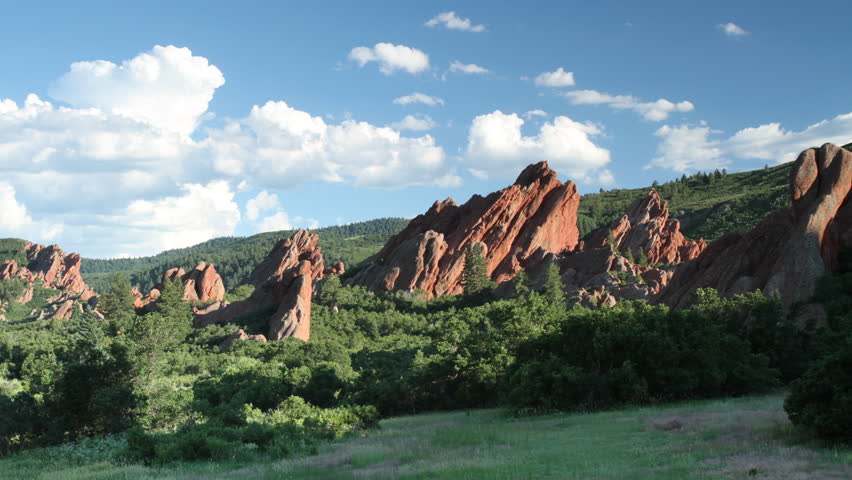 Summer cumulus clouds drift above red sandstone rocks in a Colorado State Park, on a beautiful summer evening. HD 1080p time lapse. 
