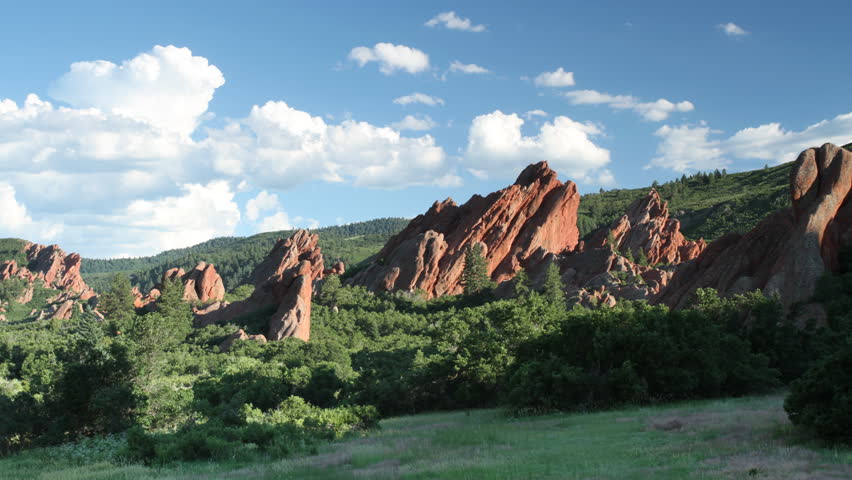 Summer cumulus clouds drift above red sandstone rocks in a Colorado State Park,