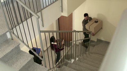 Group of three happy friends during move to new home, young people, students moving to new rental apartment with boxes, climbing stairs, going upstairs. 13 of 15