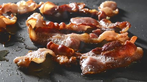 Closeup of bacon strips frying on a grill
