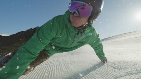 SLOW MOTION CLOSE UP: Snowboarder carving on perfectly groomed snow in mountain ski resort