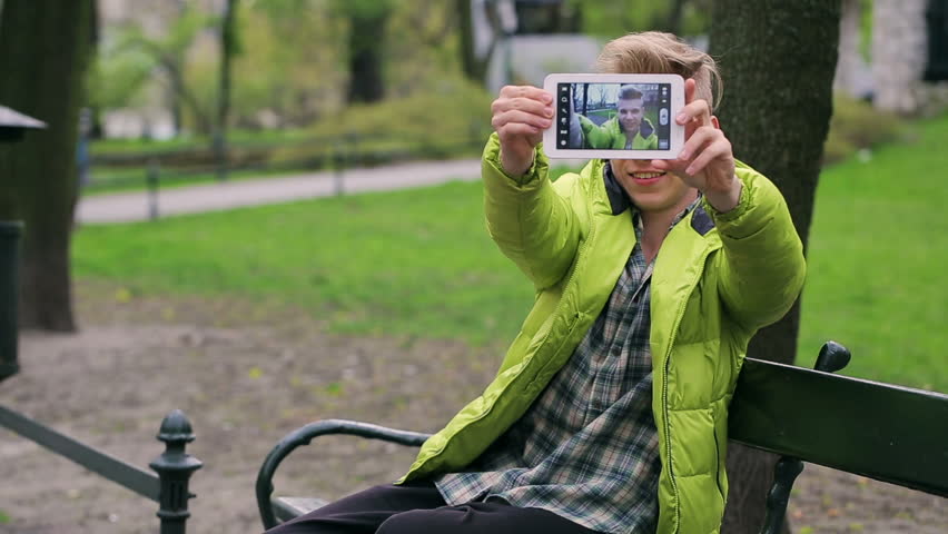 Young boy doing selfie on tablet in the park
