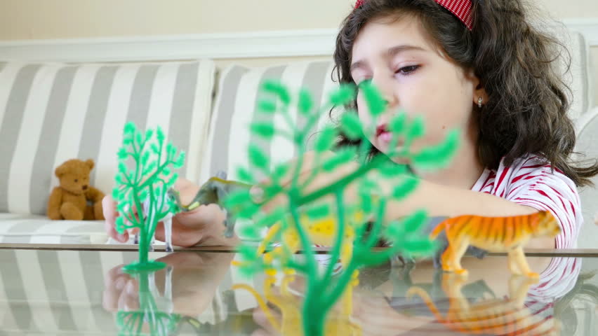Close up of a cute girl playing with animal toys on a table, dolly