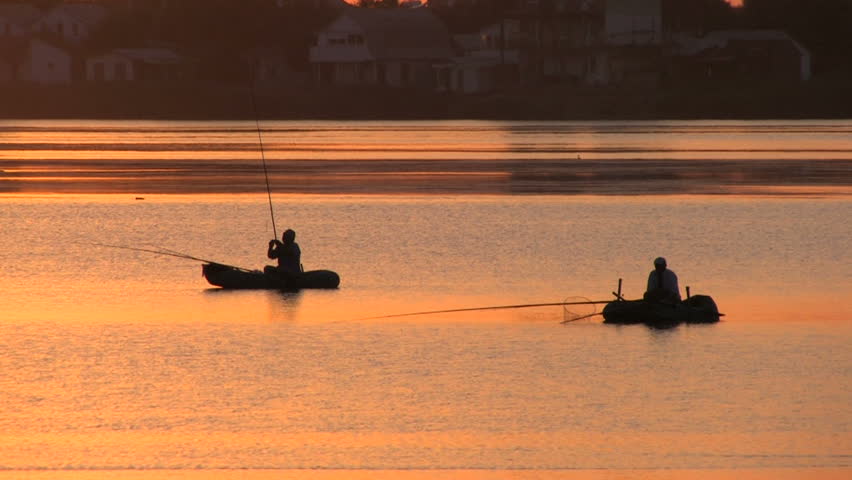 Fishing boats on the lake at Pink Sunset, village on background 