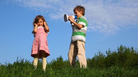 boy talking through megaphone with little girl plugging up her ears outdoor