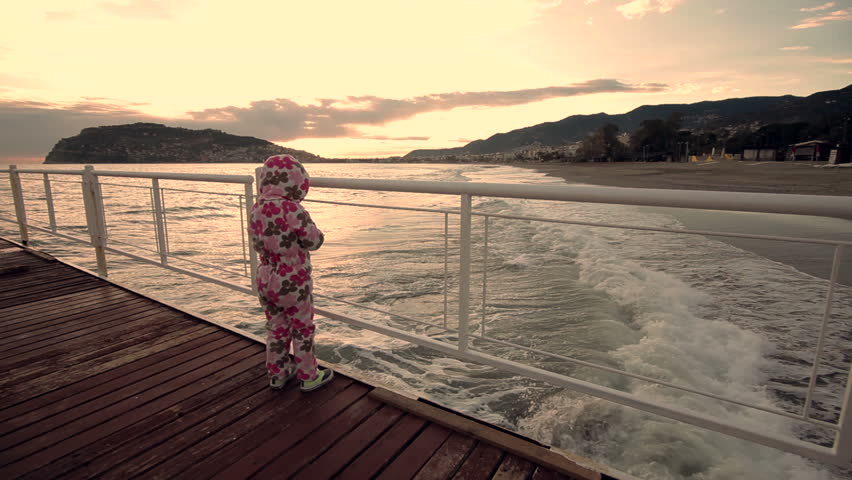 Little girl walking alone on beach at sunset 