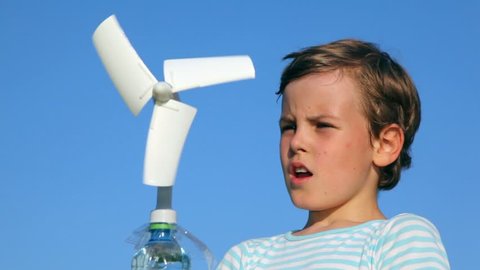 boy plays with a wind-driven generator against blue sky 