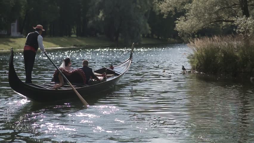 The bride and groom are sailing on a gondola on the water and hug