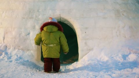 girl and her father walk in and out of igloo 