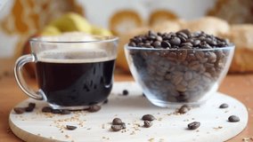 Slowmotion pouring milk in a transparent coffee cup and take it. The coffee beans on the table 