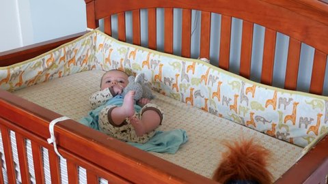 A newborn baby lying in his crib for his nap in his bedroom