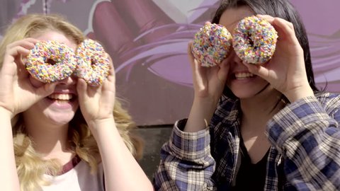 Two Teens Cover Their Eyes With Donuts And Make Silly Faces At The Camera And At Each Other (4K)