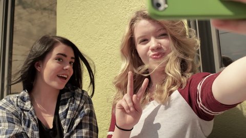Two Teens Sit Outside A Coffee Shop And Take Fun Selfies Together (4K)