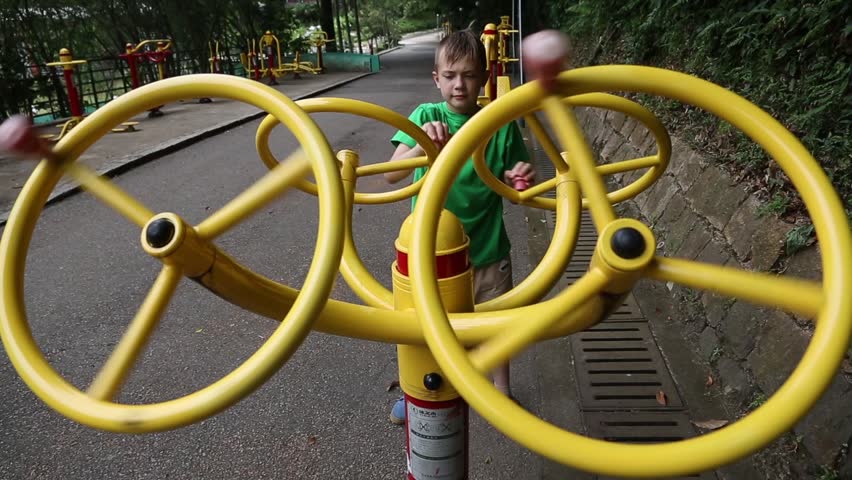 Boy does exercise on a sports simulator on the playground