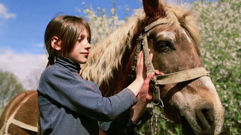 Caucasian boy teenager with a horse on nature. Rural child with a favorite pet horse. The boy takes care of his pet, a favorite horse. People, nature, animals.