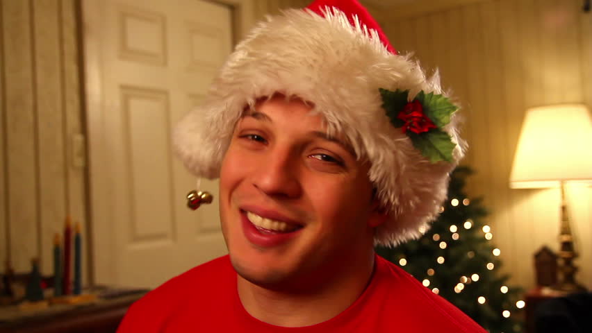 A young man in a Santa hat talks directly to camera.  Great for use on a screen